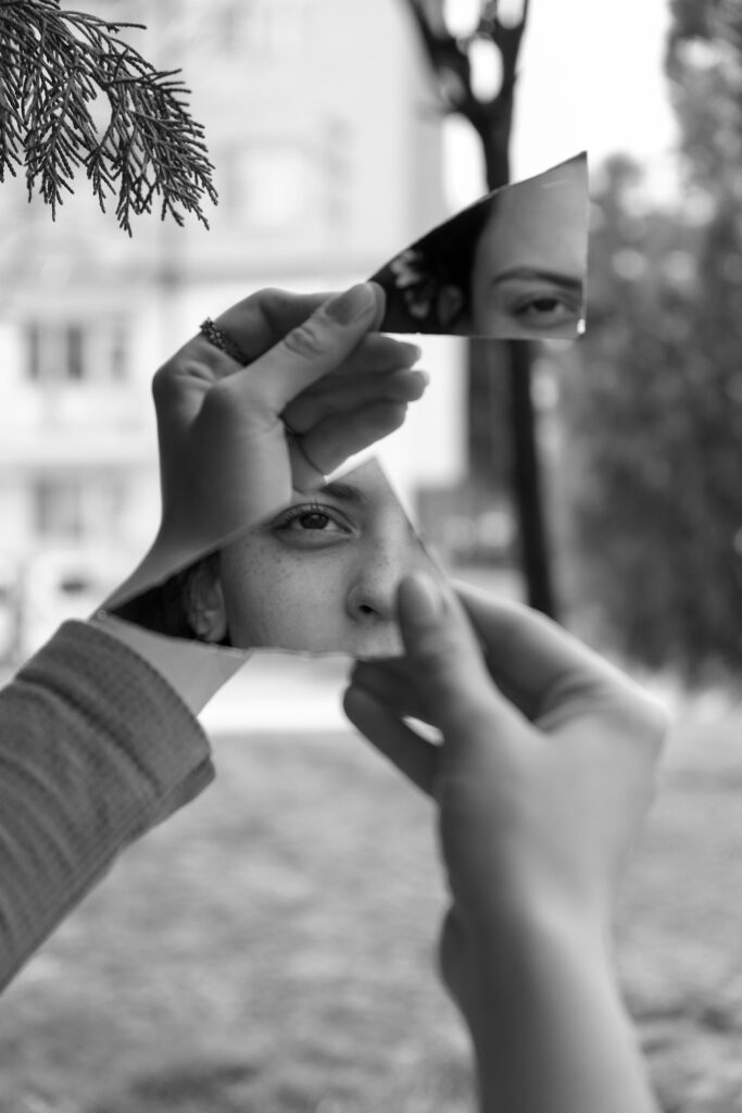 Femme tenant un fragment de miroir devant son visage, reflet fragmenté de son regard